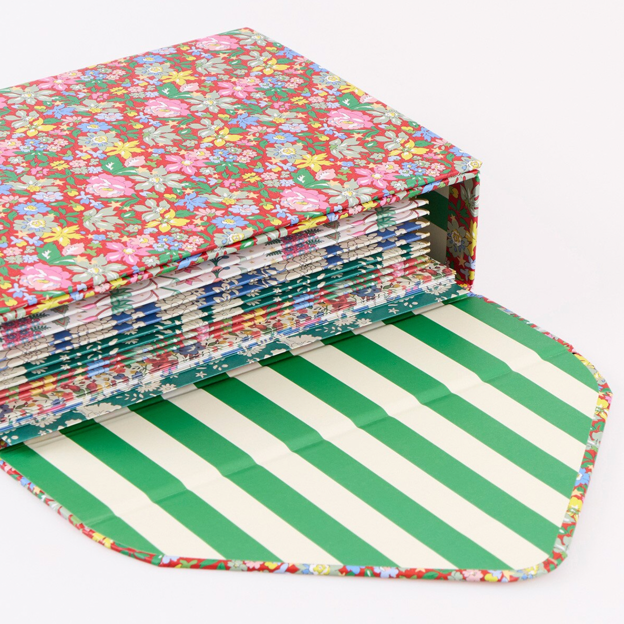 A fabric-covered binder or notebook with a multicolor floral pattern on the cover and a green-and-white striped interior, shown on a plain light background.