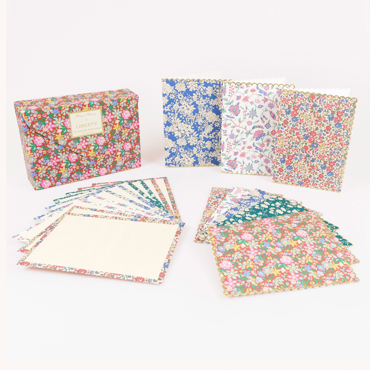 A boxed set of floral patterned paper envelopes or cardstock sheets arranged on a white background. The set includes a rectangular branded box, several folded patterned sheets, and fanned stacks of cream-colored sheets.