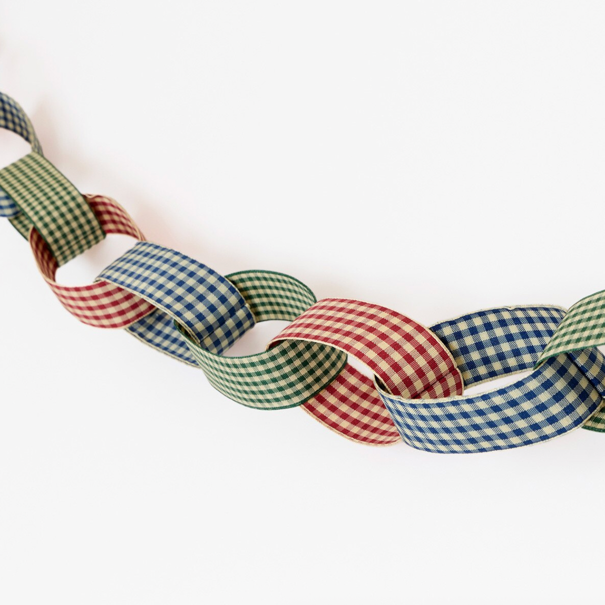 A decorative paper chain made of interlocking gingham ribbon loops in green, blue, and red, photographed against a plain white background.