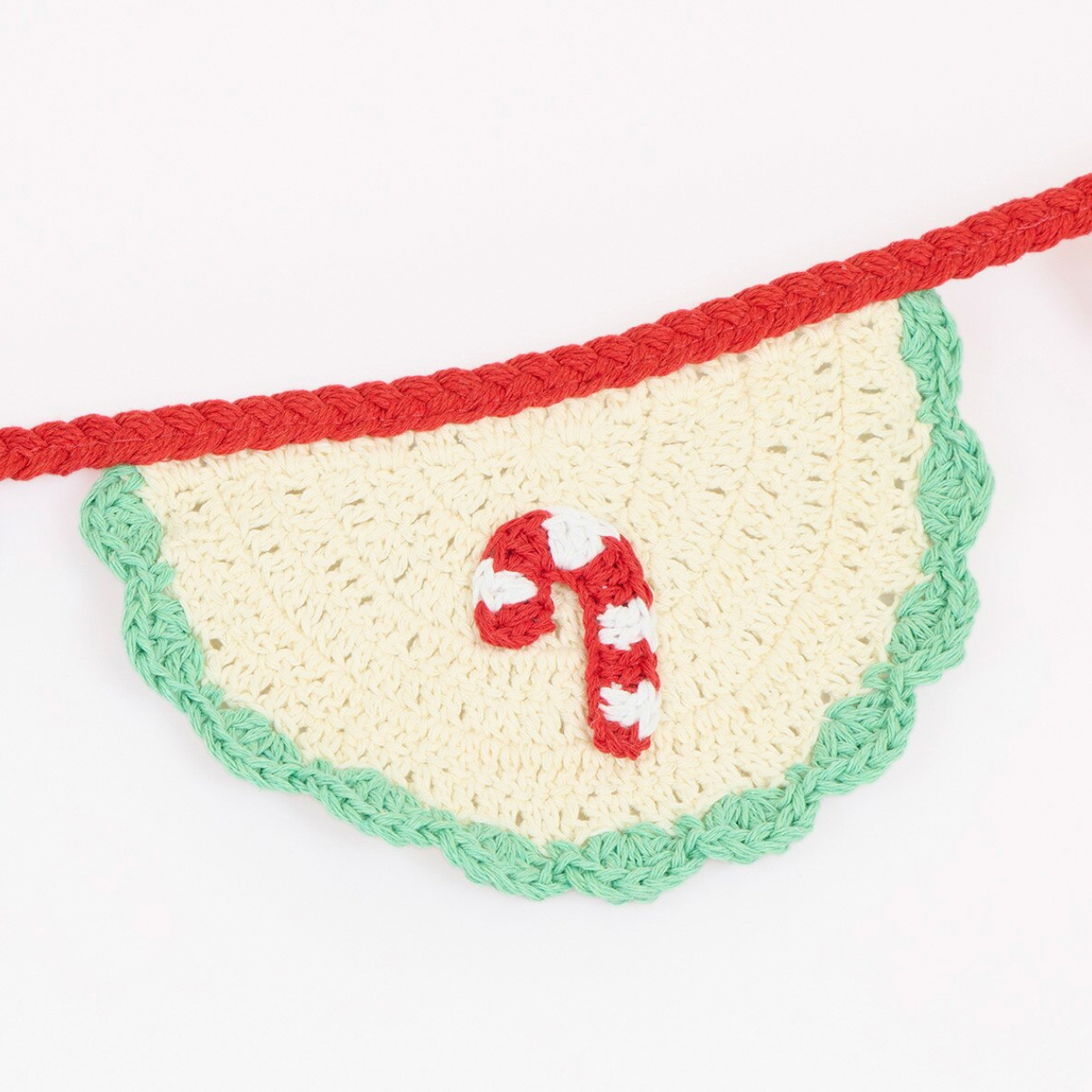 A handmade crocheted Christmas garland featuring a scalloped cream-colored semicircle panel with a green edge, a red top trim, and a red-and-white candy cane motif in the center, suspended on a white background.