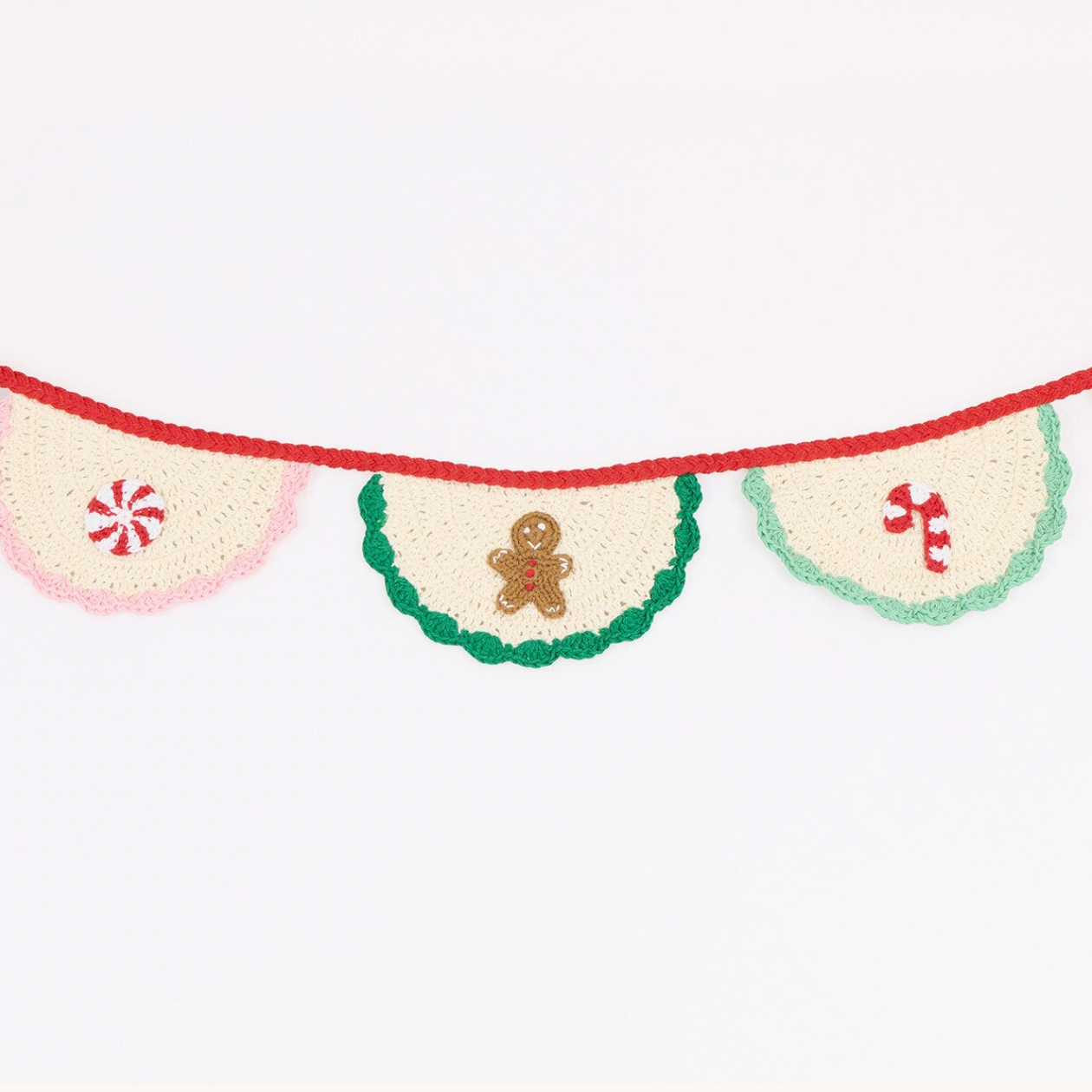A festive crocheted banner garland with three cream-colored pennants. The left pennant is light pink with a red peppermint candy motif, the center pennant is green with a green border and a gingerbread man motif, and the right pennant is light green with a red peppermint candy motif.
