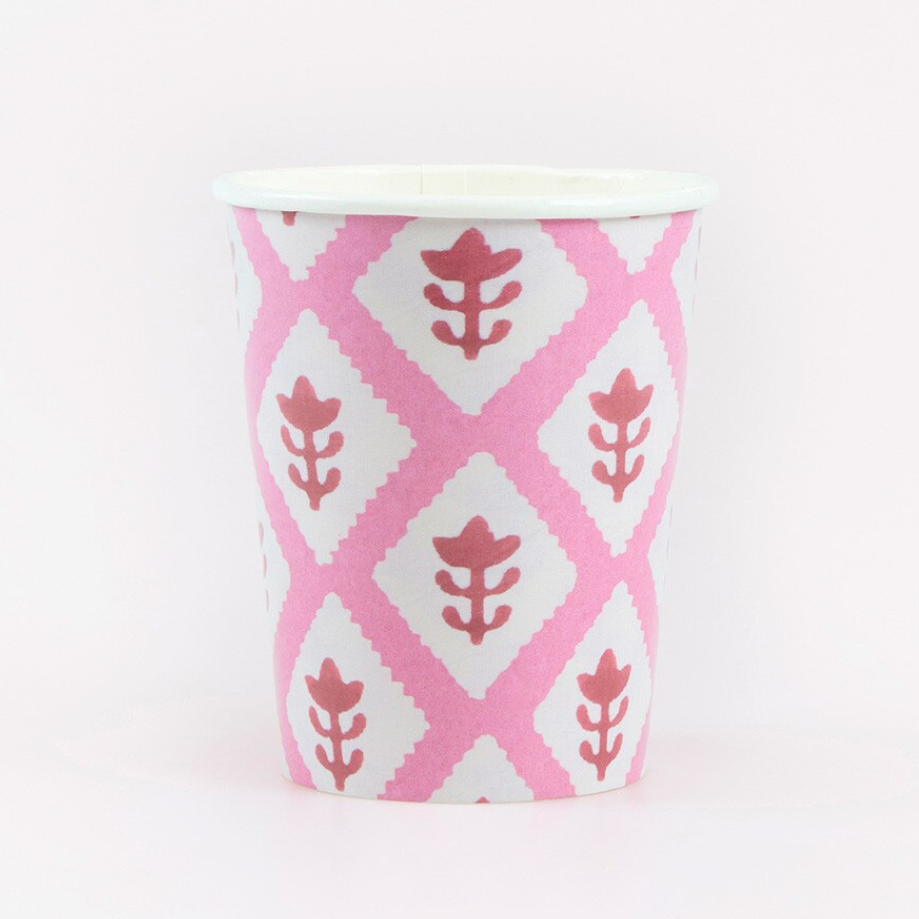 A paper cup featuring a pink and white geometric diamond pattern with stylized leaf motifs, set against a plain white background.