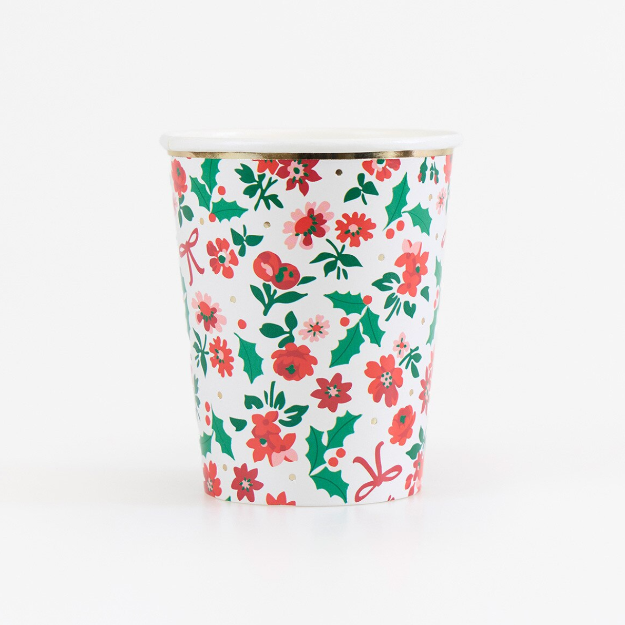 A white paper coffee cup with a festive Christmas floral pattern featuring red flowers, green holly leaves, and red bows, shown on a clean white background.
