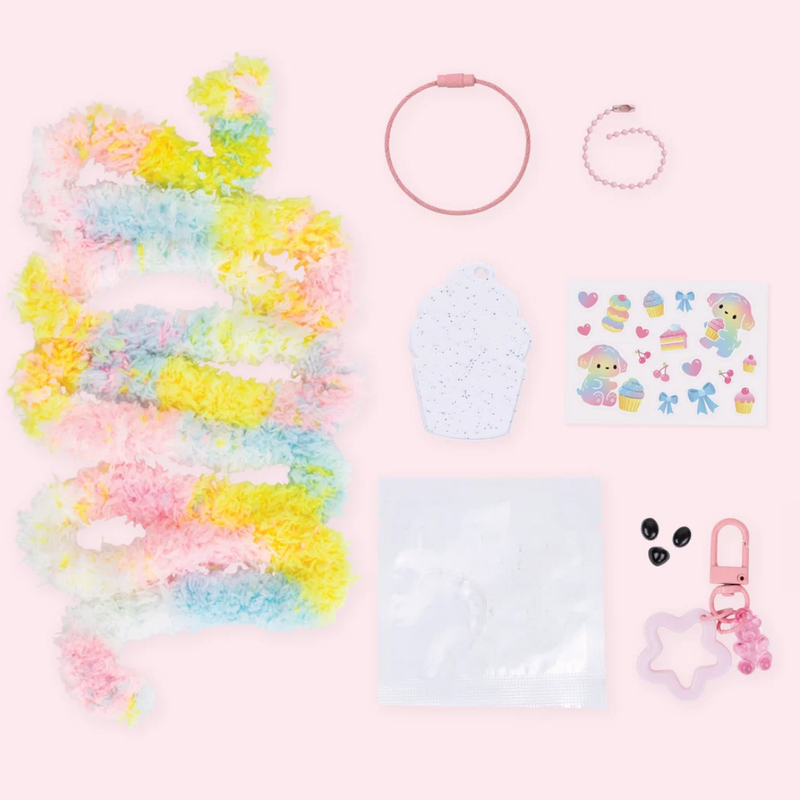 Collection of pastel-colored items including a hair tie, earrings, and keychain on a pink background