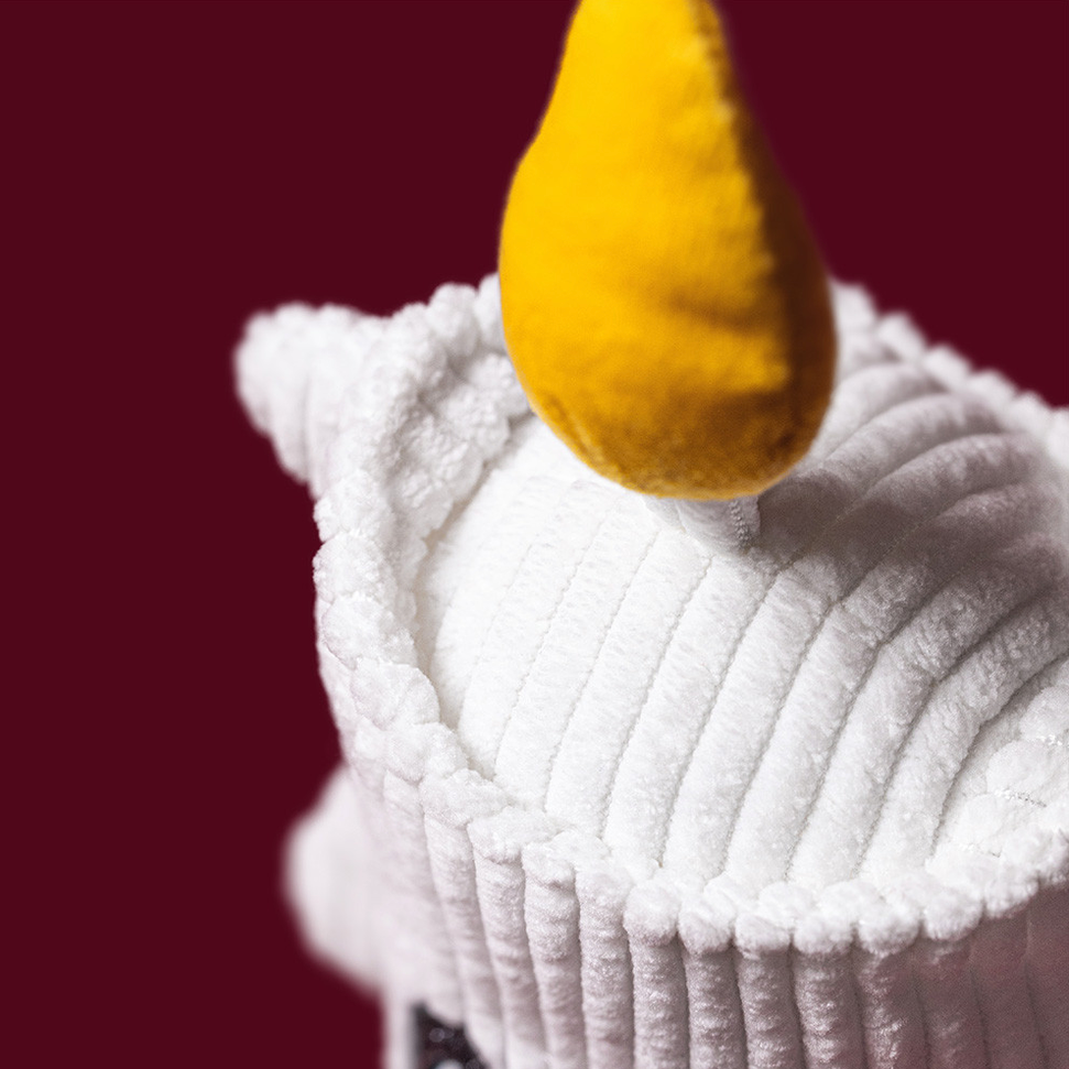 A close-up of a white ribbed plush or fleece fabric item with a bright yellow teardrop-shaped accent, set against a solid dark burgundy background.