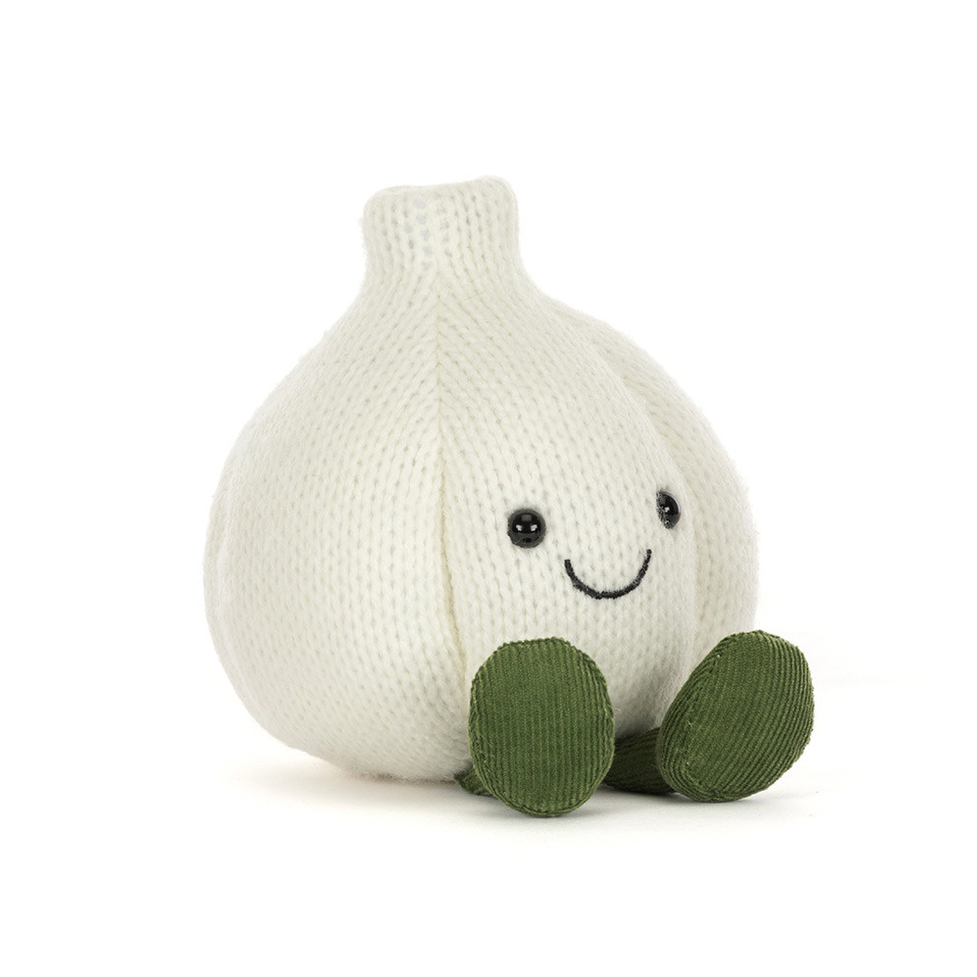 A knitted garlic plush toy in off-white with olive green feet and a simple embroidered smiley face, photographed on a clean white background.