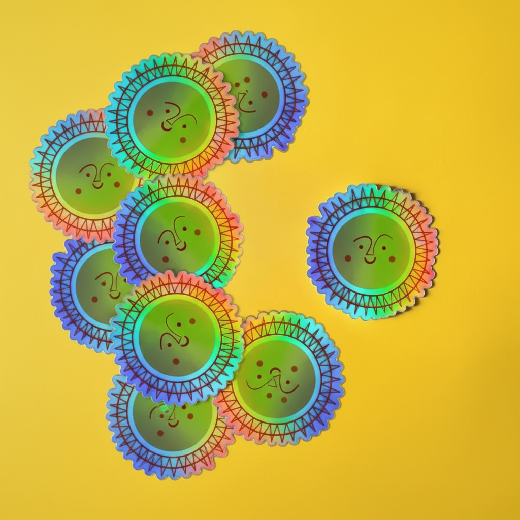 Several scalloped circular stickers or coasters with a smiling sun face design are arranged on a bright yellow background. The items have a rainbow iridescent finish shifting between green, blue, purple, pink, and orange, with dark brown line art for the face and sun rays.