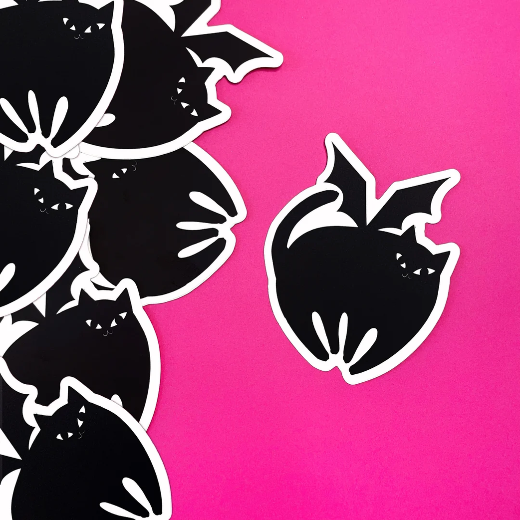 Black bat-shaped stickers with white borders arranged on a bright pink background, with several overlapping on the left and one separate sticker on the right.