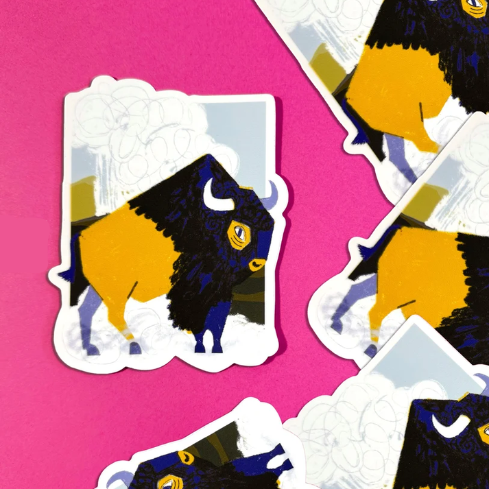 Several die-cut stickers featuring a stylized bison illustration are arranged on a bright pink background. The bison artwork is primarily black and mustard yellow with small blue and white details.