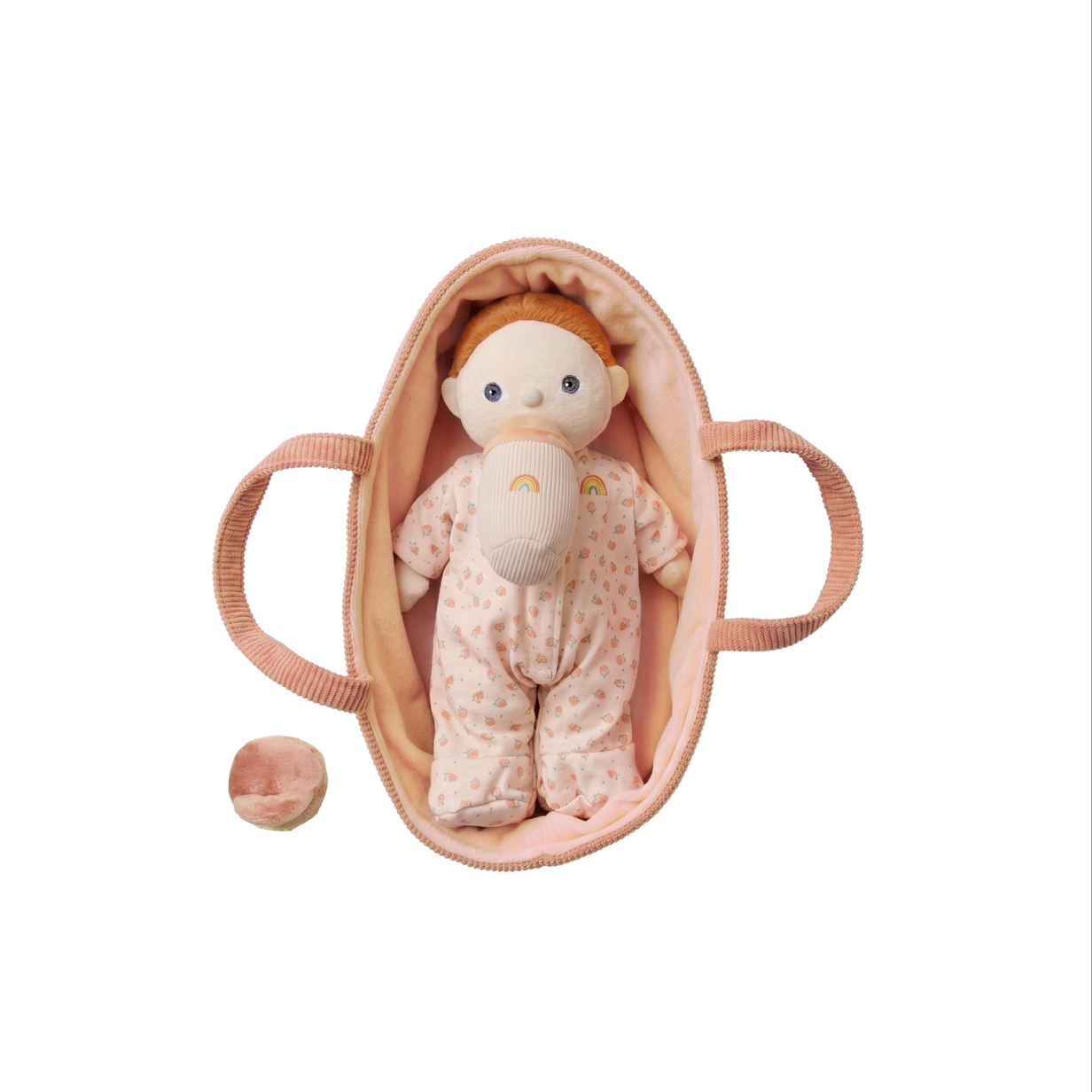 A baby doll with orange hair wearing a pink polka-dot onesie sits inside a soft pink pouch with handles, shown on a clean white background.