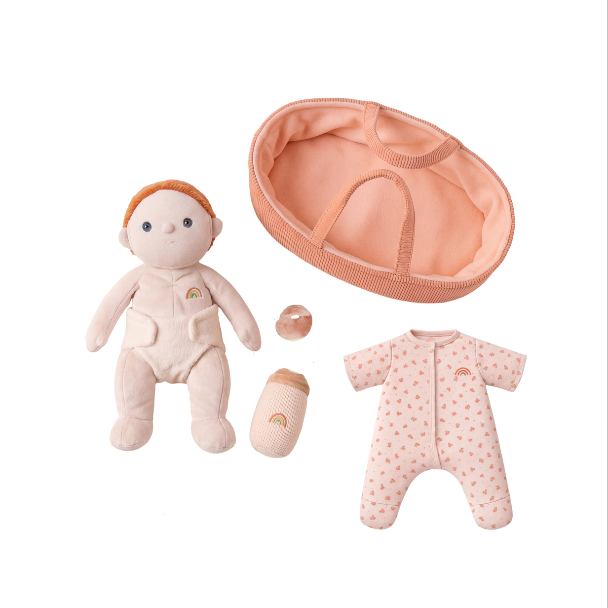 A baby doll play set on a white background, including a plush baby doll with orange hair, a peach-colored bassinet, a small bottle, and a pink patterned footmuff.