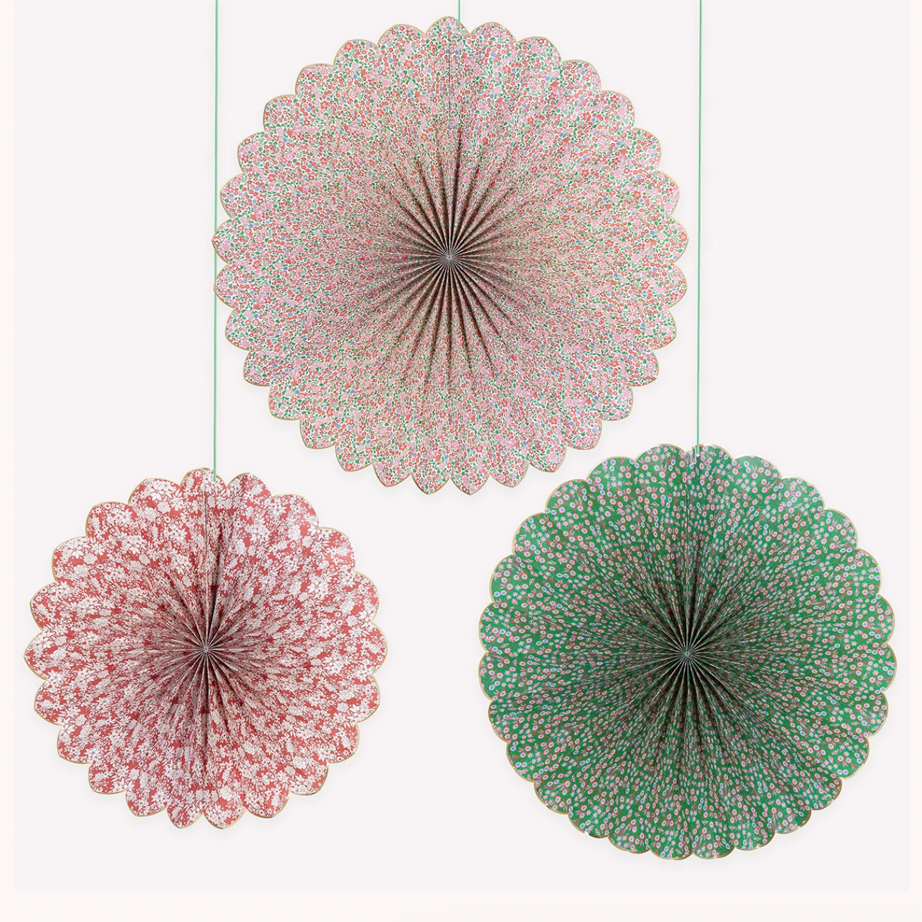 Three round paper fan decorations hanging against a plain white background, with one large fan in pink and gold and two smaller fans in pink and green.