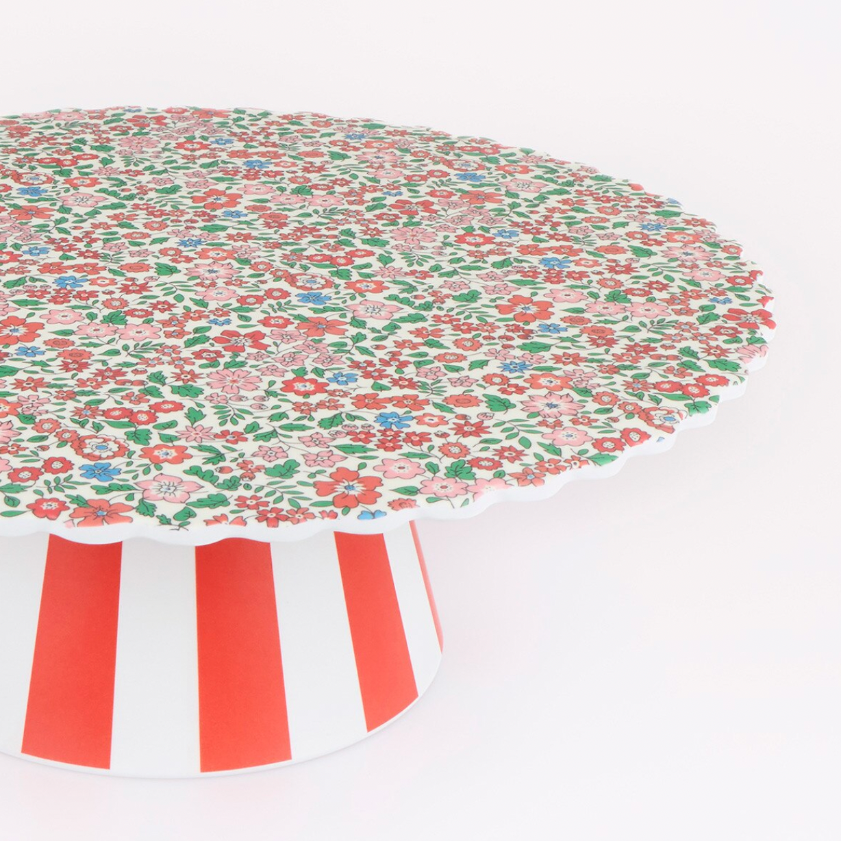 A round table with a dense red, green, and blue floral pattern on the tabletop and a white pedestal base with bold red vertical stripes, shown against a plain white background.