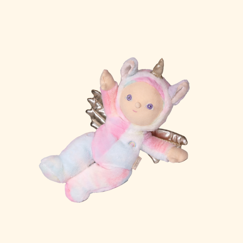 A plush toy doll dressed as a fairy, featuring pastel pink, white, and light blue gradient fabric, with metallic silver wings, a horned hood, and purple eyes, set against a solid cream background.