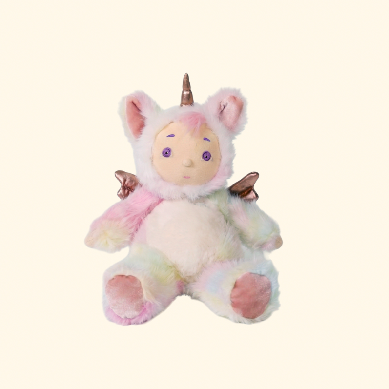 A pastel plush unicorn toy with a cream face, pink inner ears, a metallic gold horn, iridescent pink and mint fur, small metallic wings, and pink hooves, centered on a plain warm cream background.