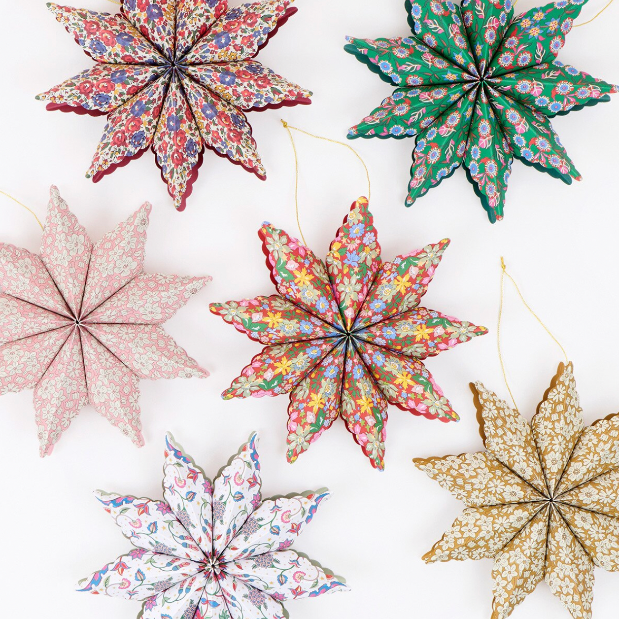 Six fabric star-shaped hanging ornaments in different floral and patterned prints, arranged on a plain white background.