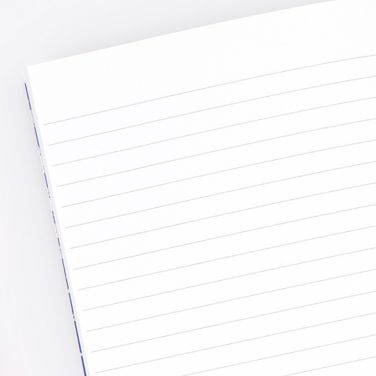 A close-up of a white ruled notepad or lined paper sheet with thin horizontal lines, photographed on a light neutral background.