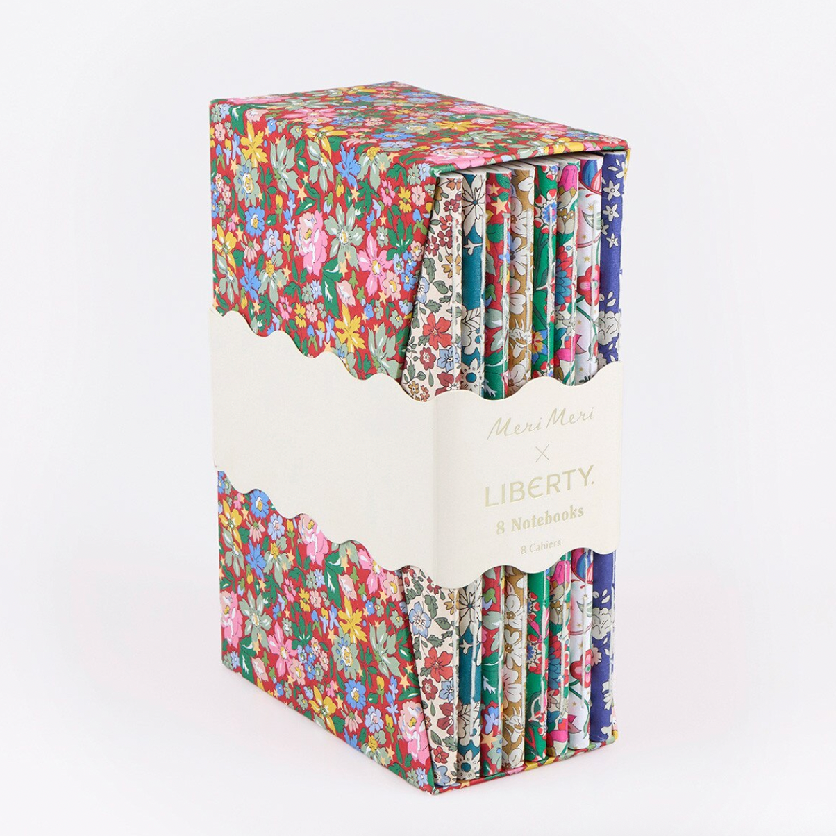 A boxed set of notebooks with a colorful floral and patterned cover, wrapped in a white paper band labeled 'Mini Meri x LIBERTY x Notebooks'.