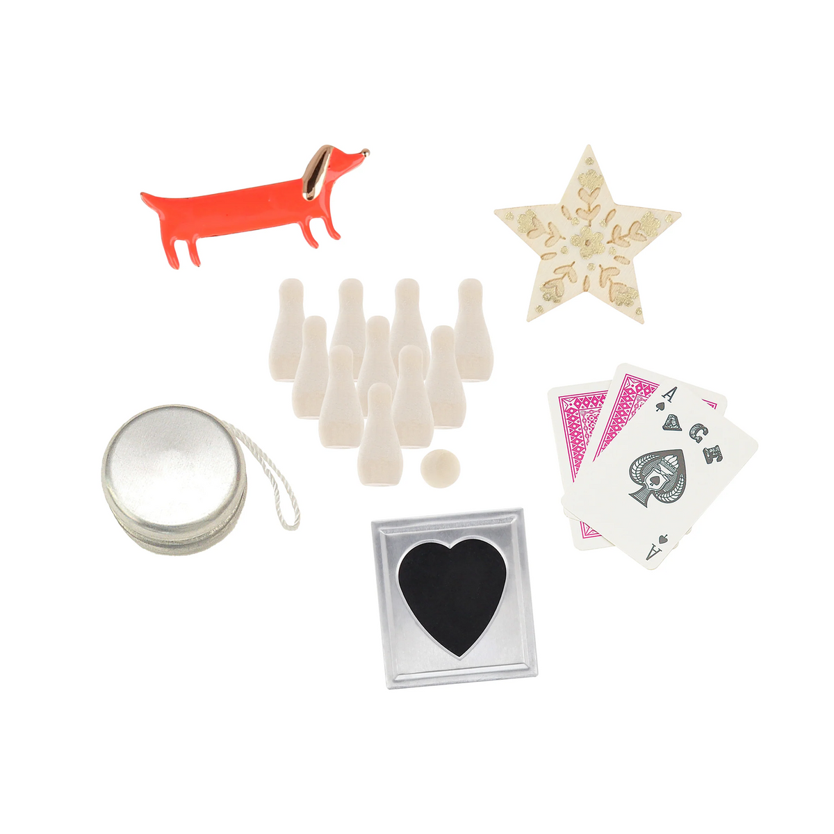 A dachshund-shaped orange metal pin, a cream-colored wooden star, a silver metal bowl with a white chain, a set of white plastic bowling pins and balls, a square silver frame with a black heart-shaped insert, and a fan of playing cards on a white background.
