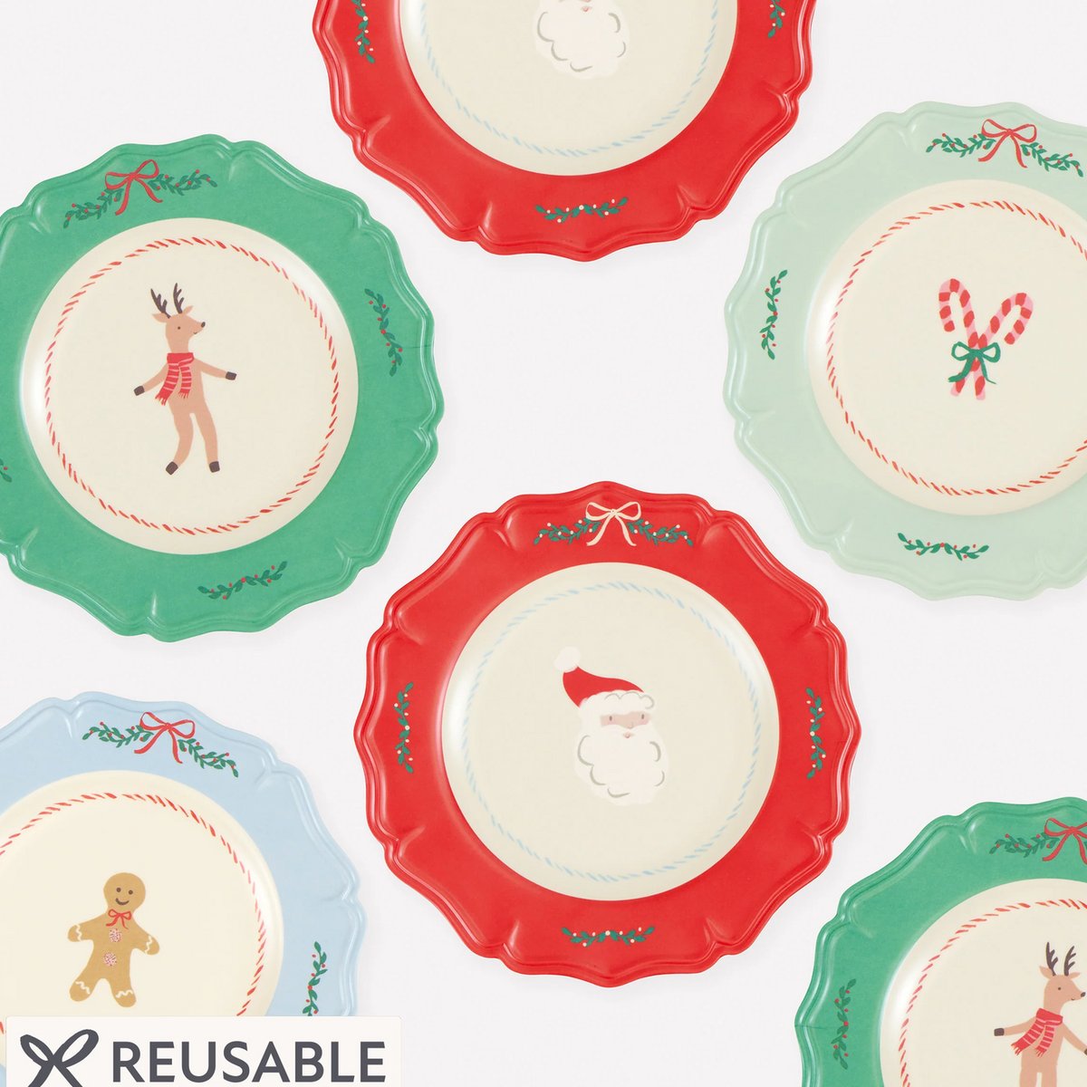 A set of reusable ceramic plates with scalloped edges, shown in multiple holiday colors including red, green, light blue, and mint. Each plate features a festive illustration in the center, such as Santa Claus, a reindeer, a gingerbread man, or candy canes, surrounded by a white center.