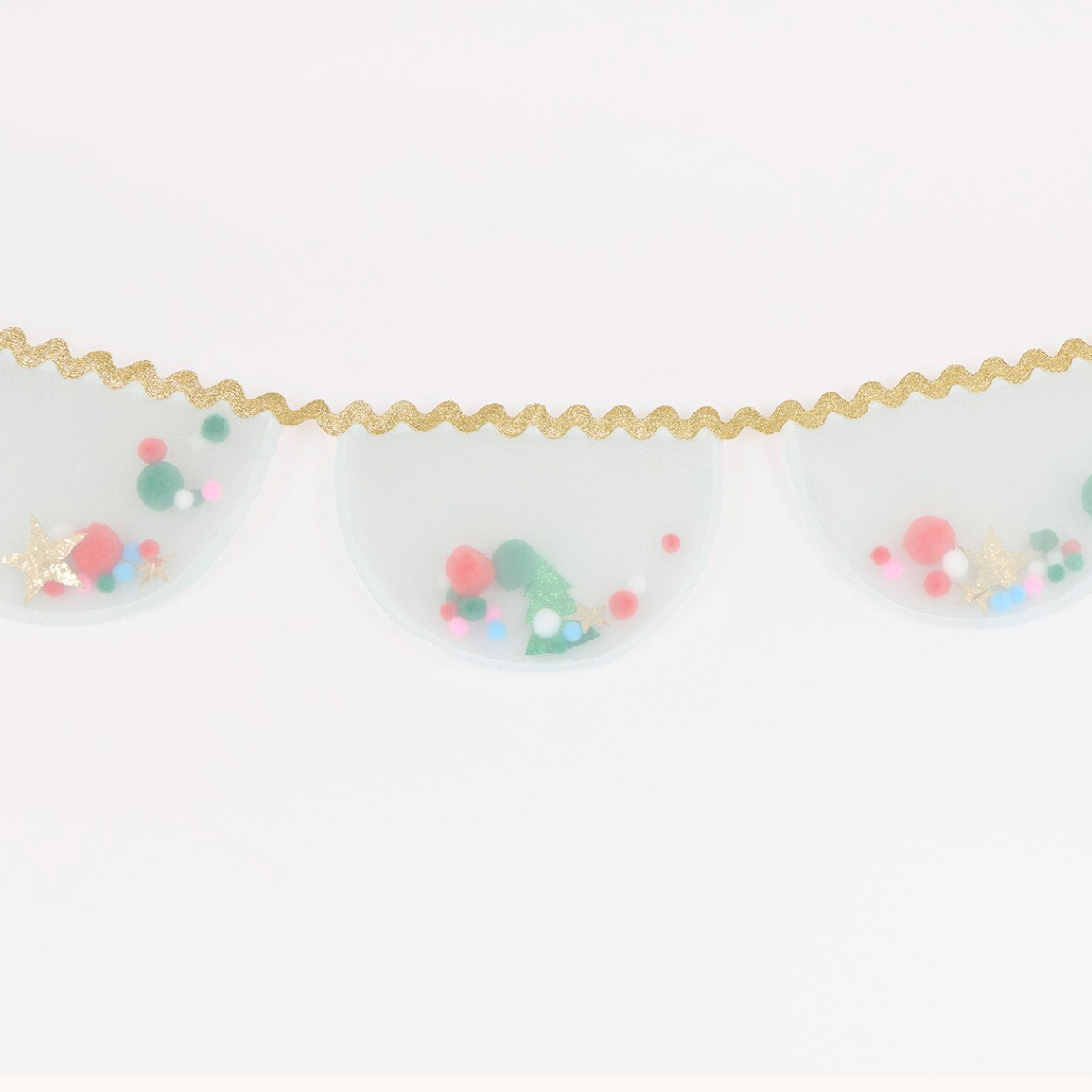 A close-up of a decorative garland featuring three translucent white oval panels filled with colorful pom-poms and small gold star accents, suspended by a wavy gold glittery string against a plain white background.