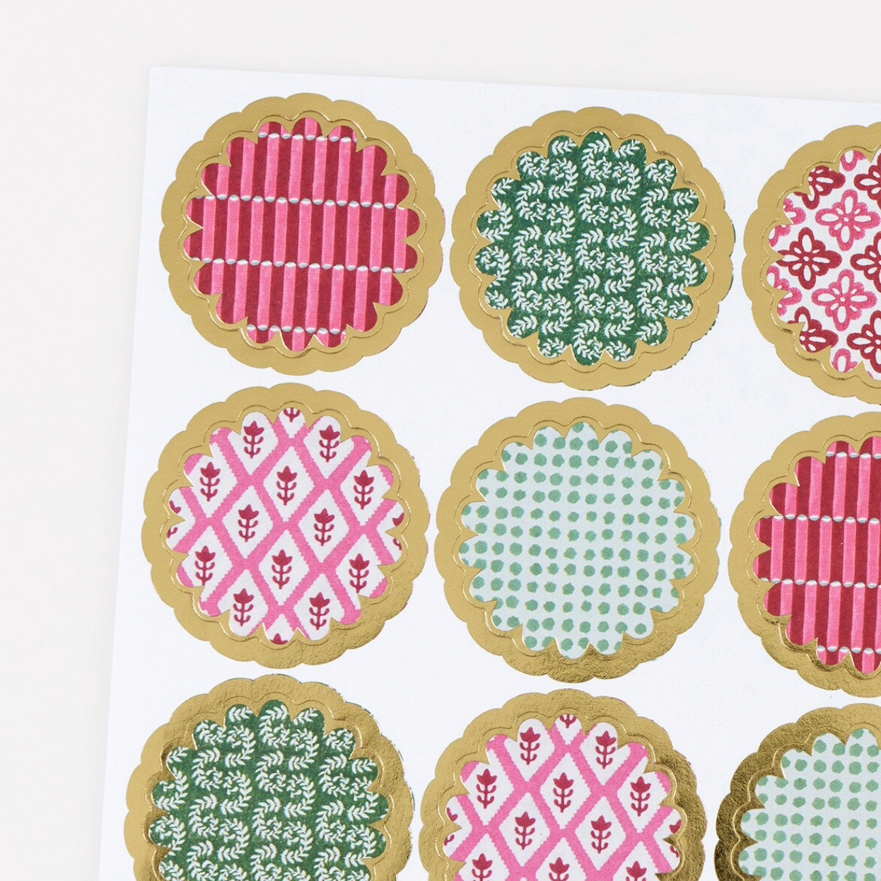 A sheet of round scalloped stickers with gold borders, featuring various colorful patterns including pink and green stripes, floral motifs, and polka dots on a white background.