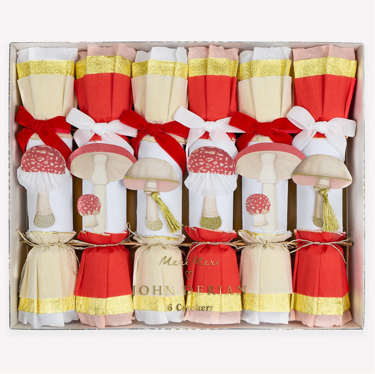 A boxed set of Christmas cracker ornaments styled as mushrooms with red and cream bodies, white bows, gold glitter bands, and red-and-white spotted caps, arranged in a gift box.