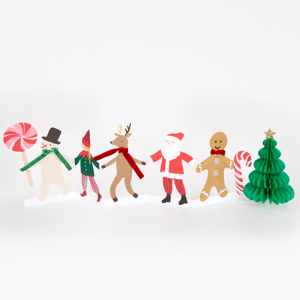 A set of colorful Christmas-themed paper cutout figures and decorations arranged on a white surface against a white background. The set includes a snowman holding a lollipop, an elf, a reindeer, Santa Claus, a gingerbread man, and a green Christmas tree with a star topper, alongside candy cane props.
