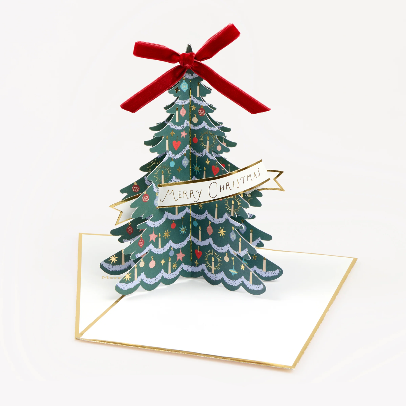 A 3D pop-up Christmas tree greeting card on a white card base with a gold border, featuring a green tree decorated with red ornaments and a red velvet bow on top, with a banner reading 'Merry Christmas'.
