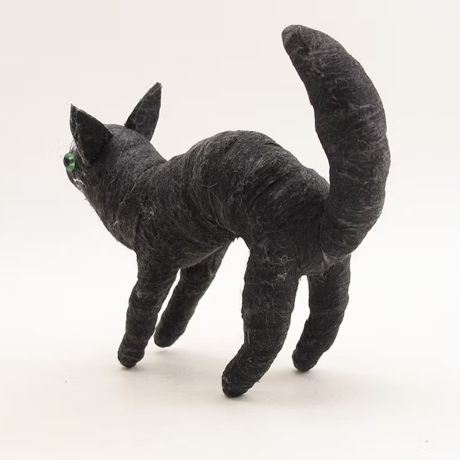 A small black cat figurine with textured fur and bright green eyes, standing on a plain white background.
