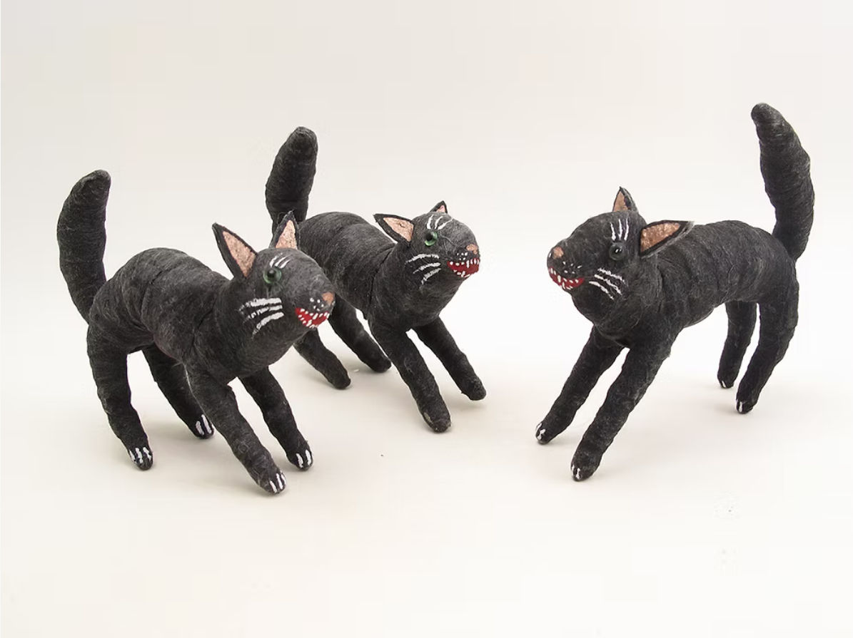 Three black cat figurines with hand-painted details, including white whiskers, green eyes on one, and red and white open mouths, displayed on a plain light background.