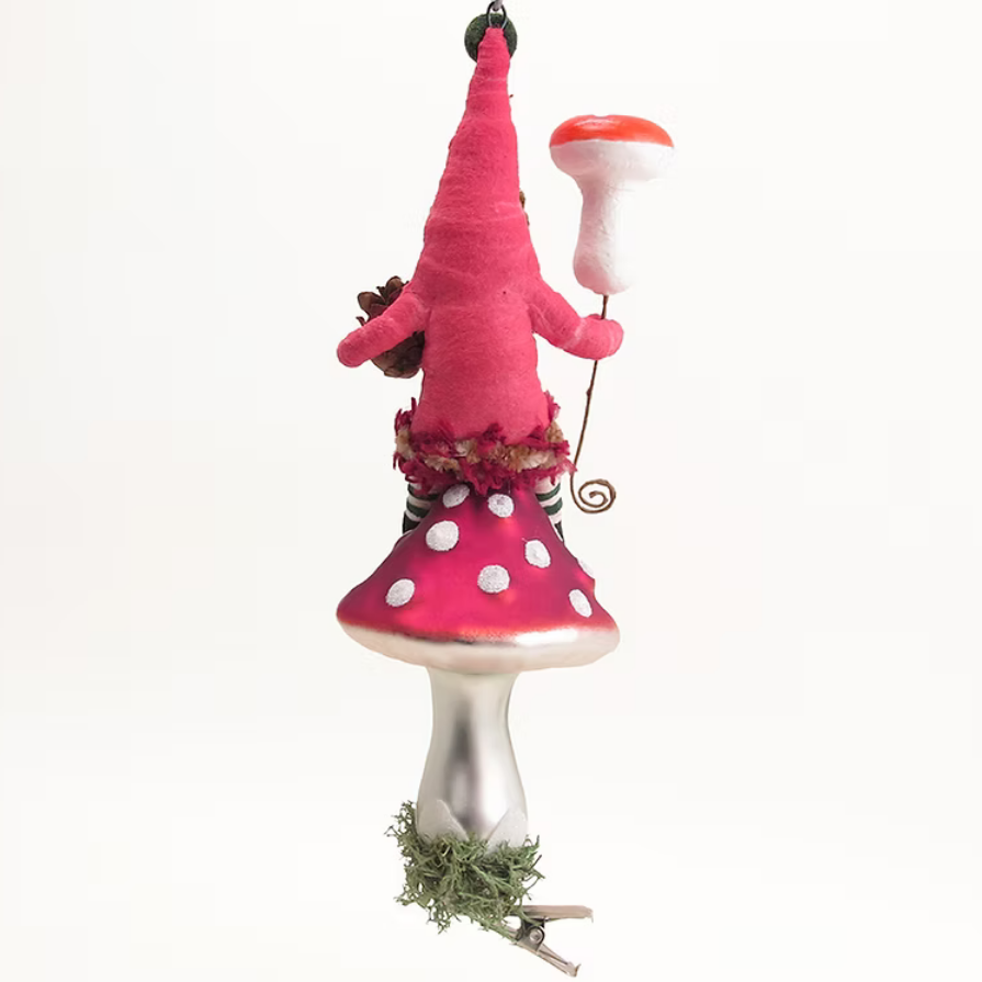 A whimsical fairy ornament shaped like a mushroom, featuring a bright pink felt gnome with a tall pointed hat, white polka dots on the cap, a silver stem, and a small sprig of greenery at the base, set against a plain white background.