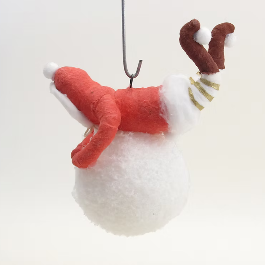 A handmade felt Christmas ornament shaped like a Santa Claus figure lying on a fluffy white ball, hanging from a metal hook against a plain white background.