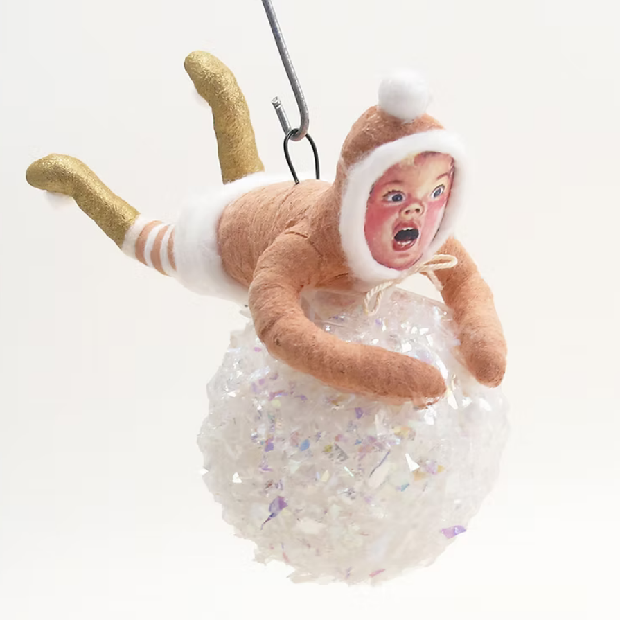 A novelty hanging ornament shaped like a baby figure wearing a tan hooded outfit with white trim, gold glittery legs, and a clear plastic bubbly belly, suspended against a plain white background.