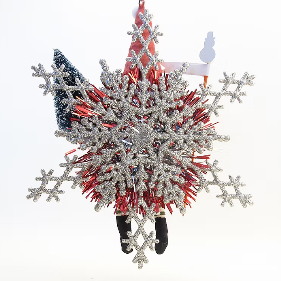 A festive Christmas ornament shaped like a hanging Santa figure, featuring a large glittery silver snowflake, red and white striped hat, blue beard, and black boots, set against a plain white background.