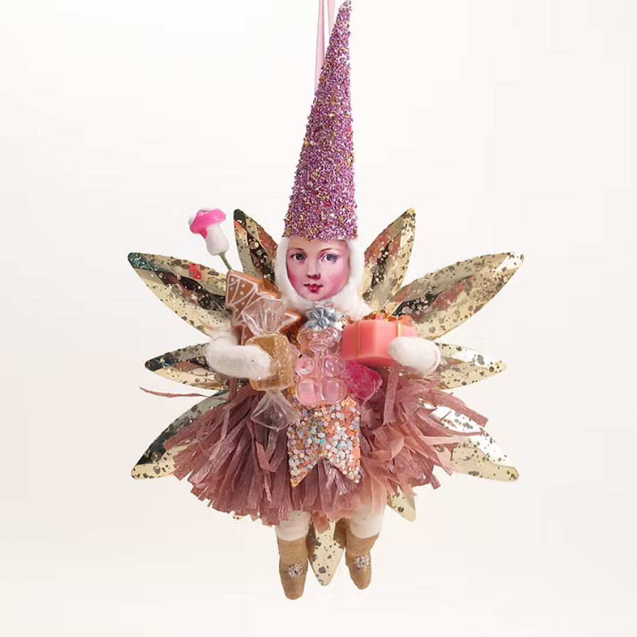 A whimsical fairy-themed hanging ornament featuring a small doll with a glittery purple conical hat, pink tulle skirt, gold sequined wings, and a pink floral accessory, photographed against a plain white background.