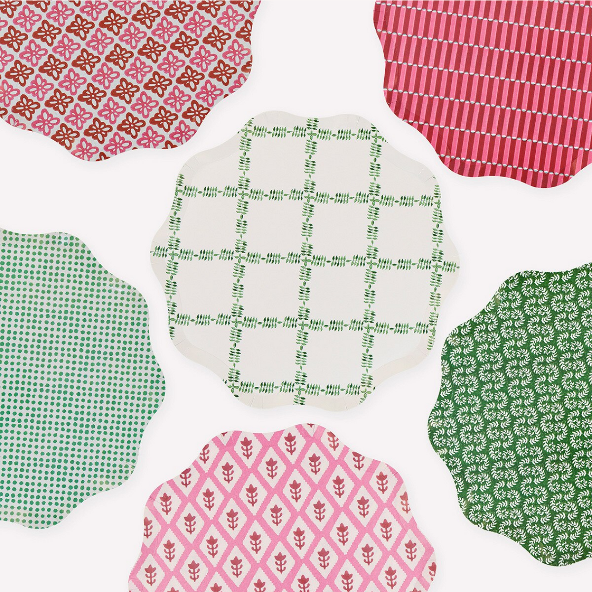 Six scalloped-edge fabric napkins with different colorful patterns are arranged in a circle on a white background.