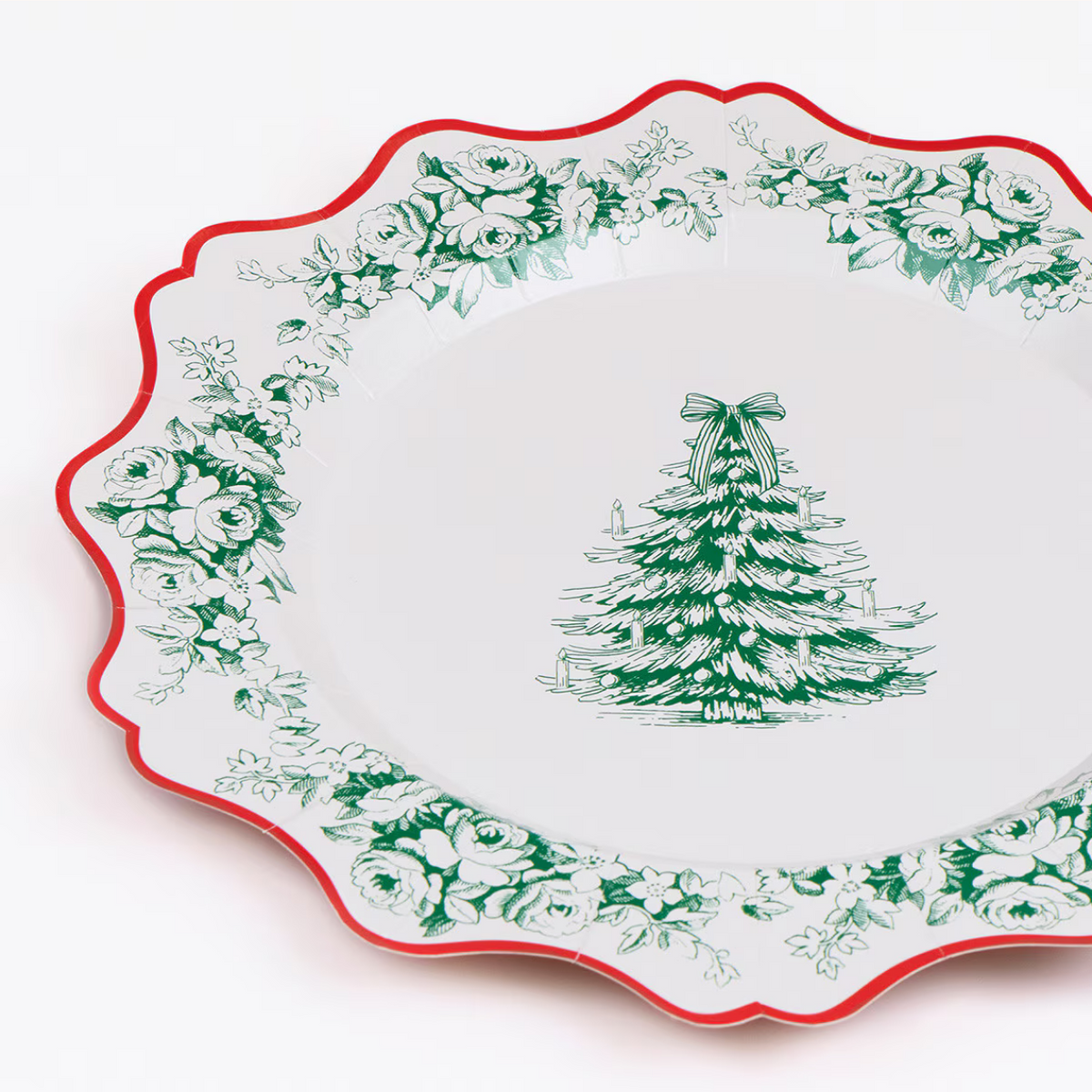 A white ceramic serving platter with a scalloped edge, featuring a green Christmas tree illustration in the center and a border of green floral toile-style print, finished with a thin red rim.