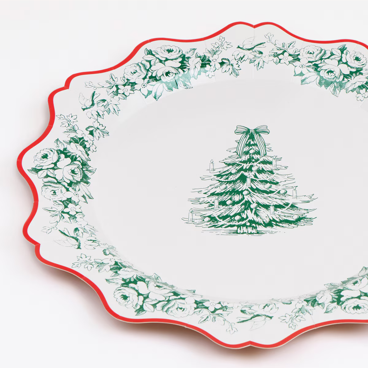 A white ceramic platter with a scalloped edge, featuring a green floral border and a green mistletoe tree illustration in the center, with a thin red rim.