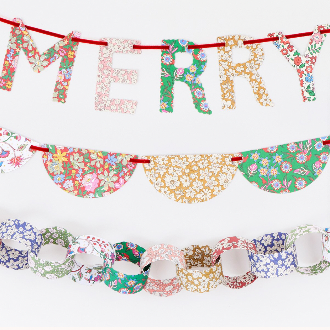 A festive paper garland set featuring a 'MERRY' letter banner, a scalloped banner, and paper chain links, all decorated with colorful floral patterns on a white background.