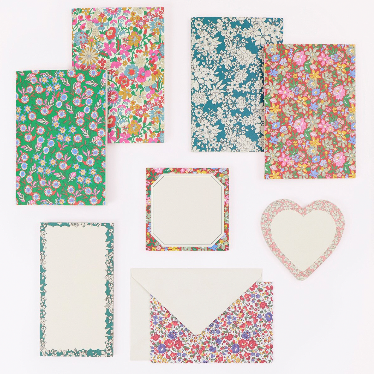 A coordinated stationery set featuring floral and botanical patterned paper pieces, including cards, envelopes, and a heart-shaped card, arranged on a plain white background.