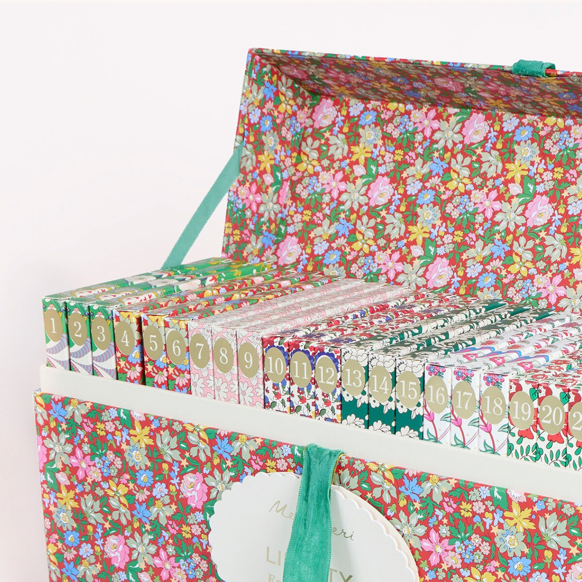 A floral-patterned gift box with a hinged lid, filled with small decorative boxes and cards. The boxes feature a dense multicolor floral print with pink, green, blue, yellow, and white flowers on a warm red-brown background.