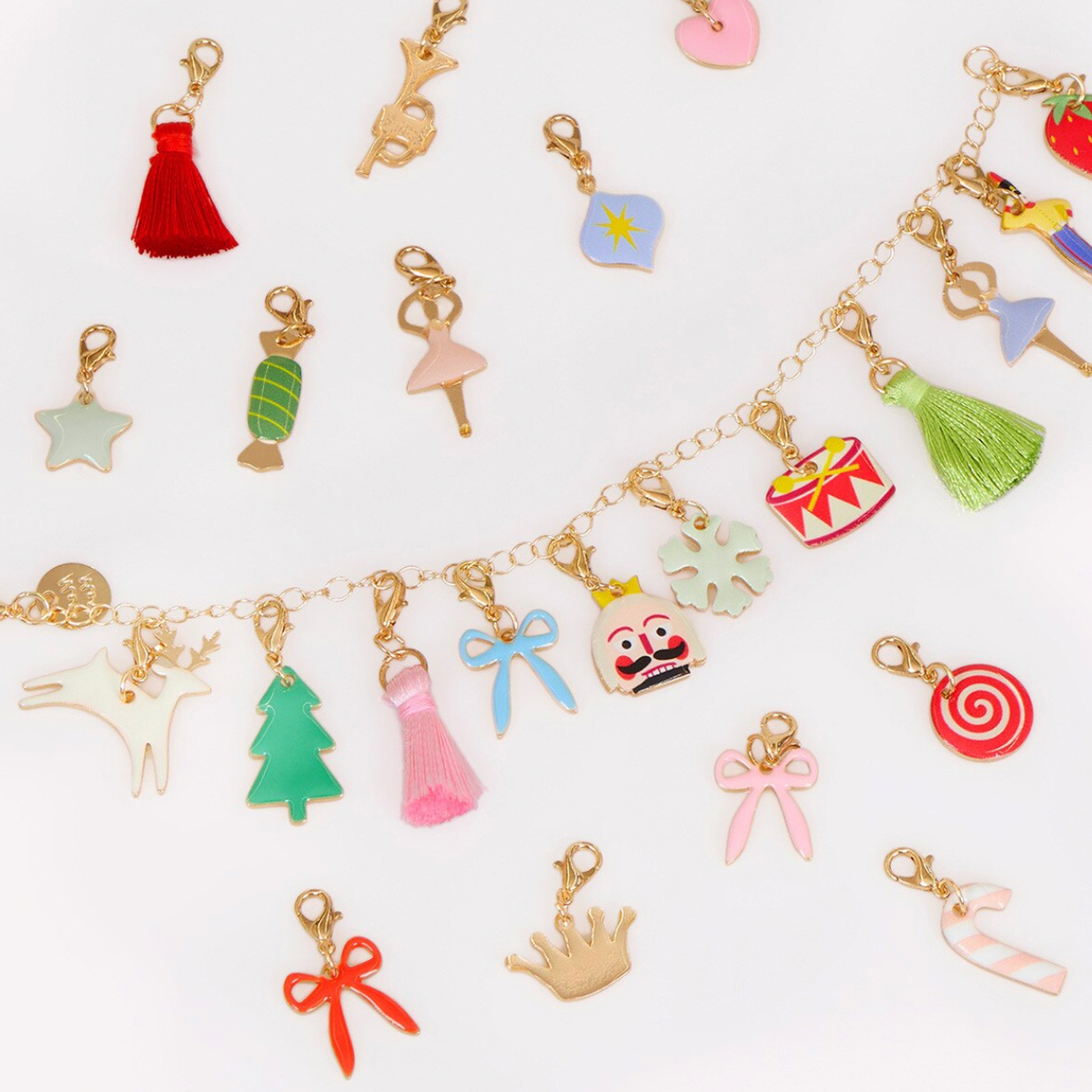 A gold-tone chain bracelet decorated with multiple colorful enamel charms shaped like a candy cane, Christmas tree, dress, bow, clown face, snowflake, and other festive motifs, displayed on a clean white background.