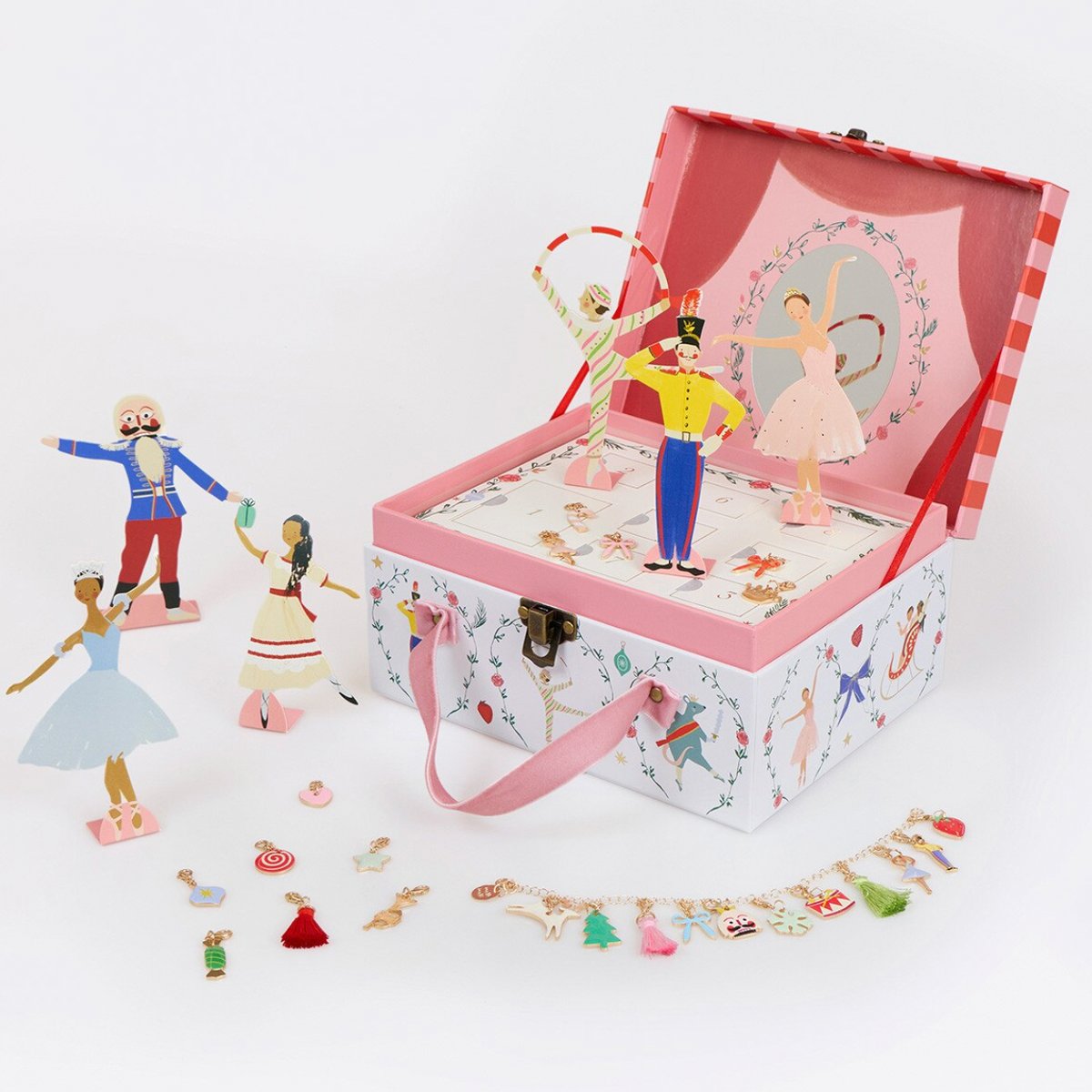 A decorative music box case with ballet and circus-themed illustrations, shown open with miniature figurines and accessories arranged around it on a white background.