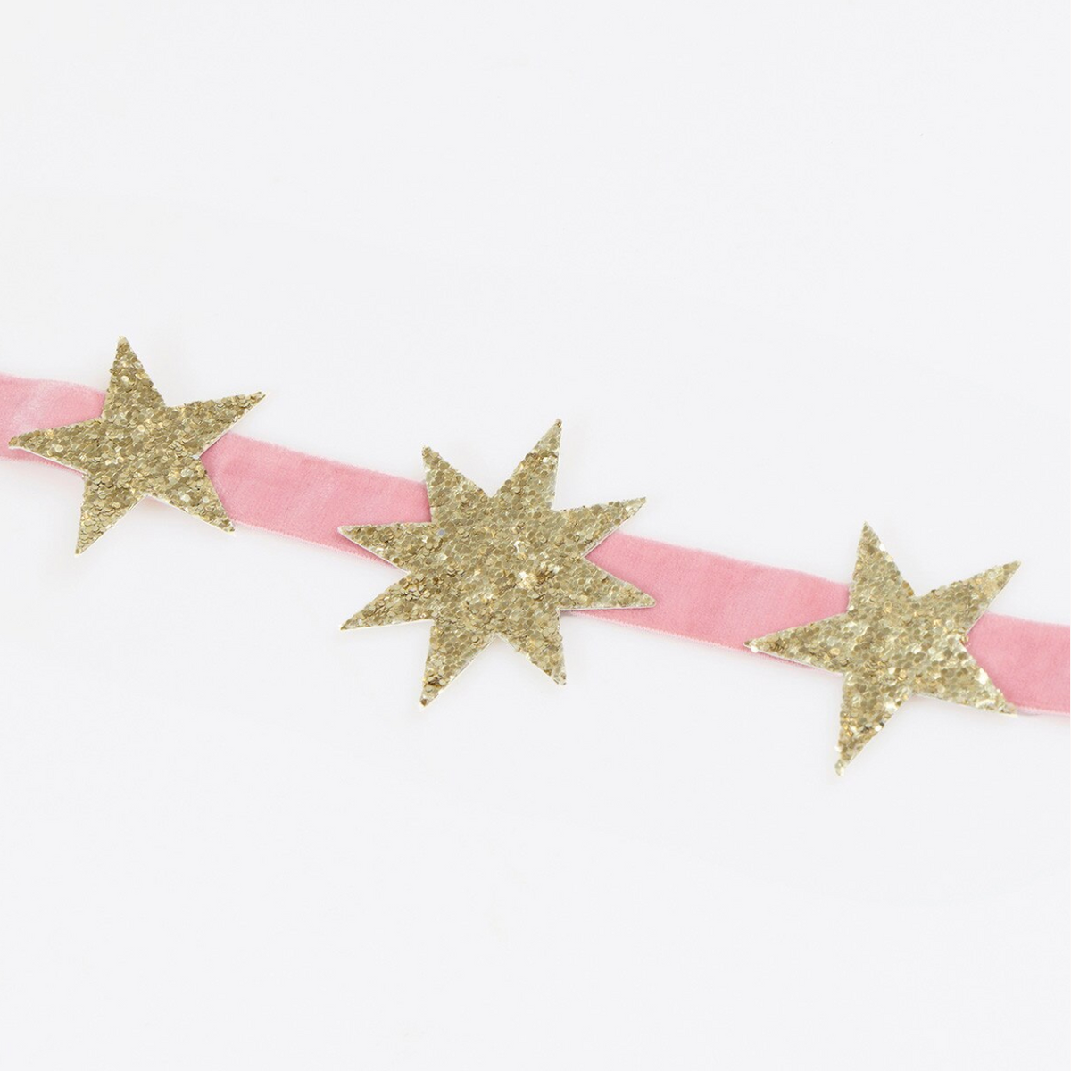 A pink velvet headband decorated with three glittery gold star-shaped embellishments, shown against a plain white background.