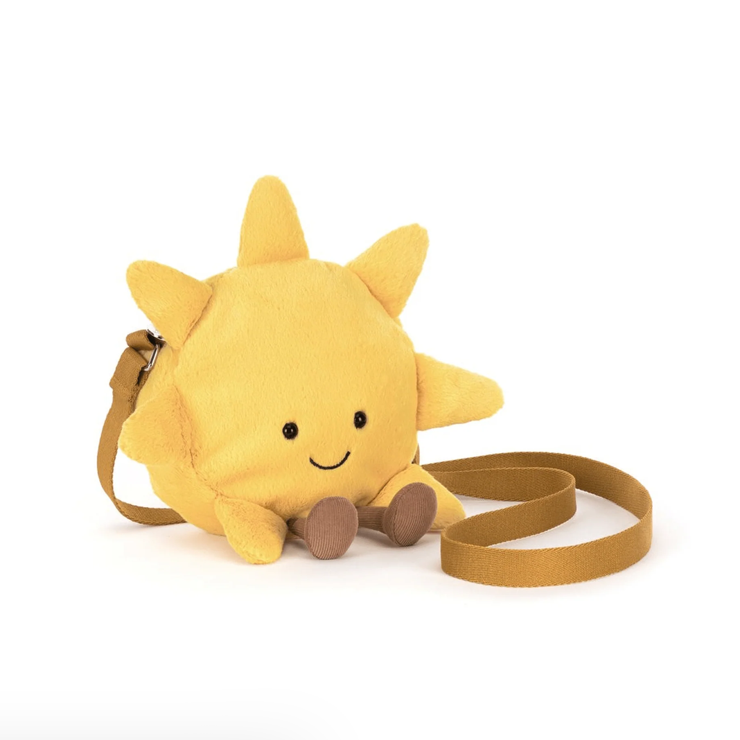 A yellow plush sun-shaped crossbody bag with a smiling face, small brown feet, and a tan shoulder strap, shown on a white background.