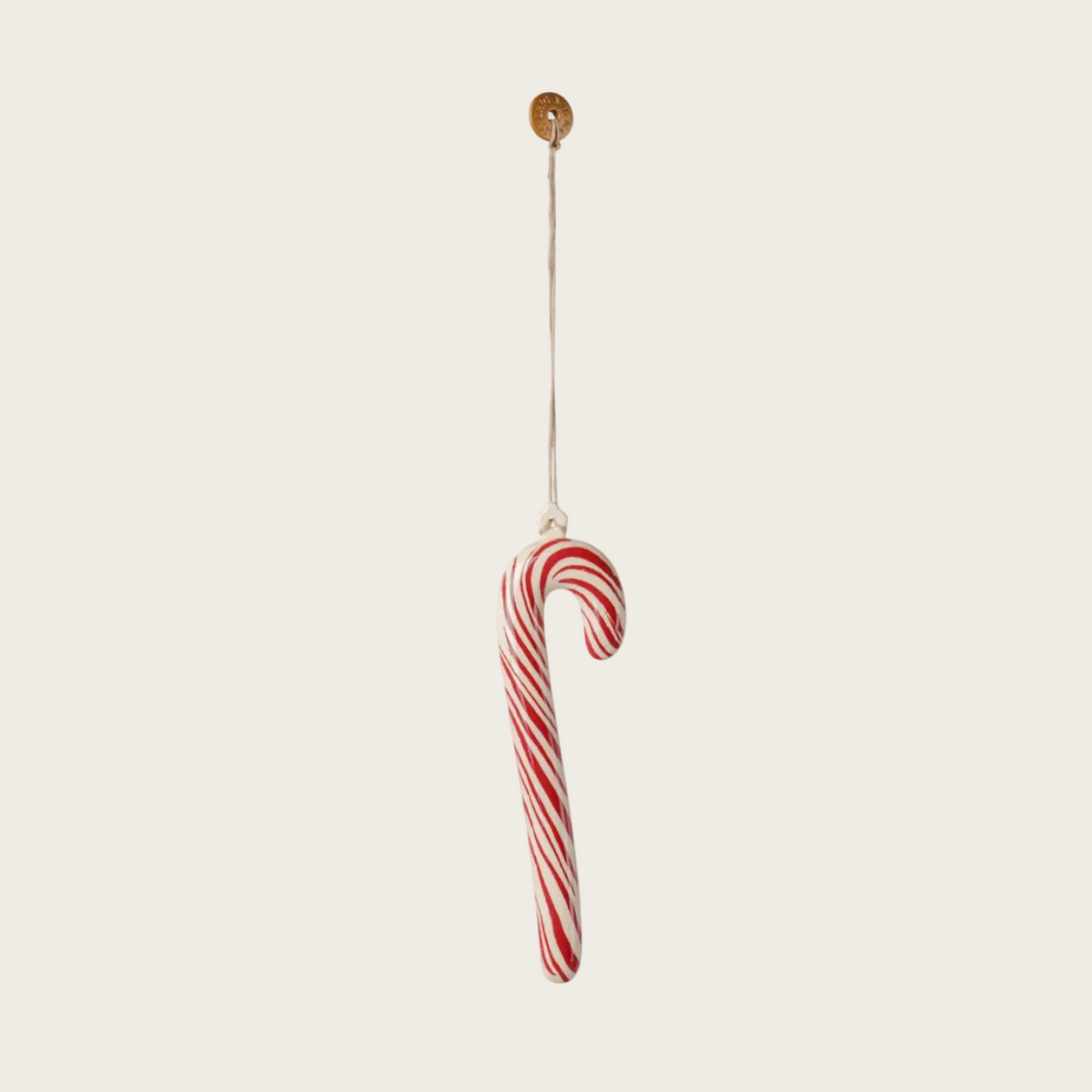 A single red-and-white striped candy cane hanging from a thin string against a plain light background.