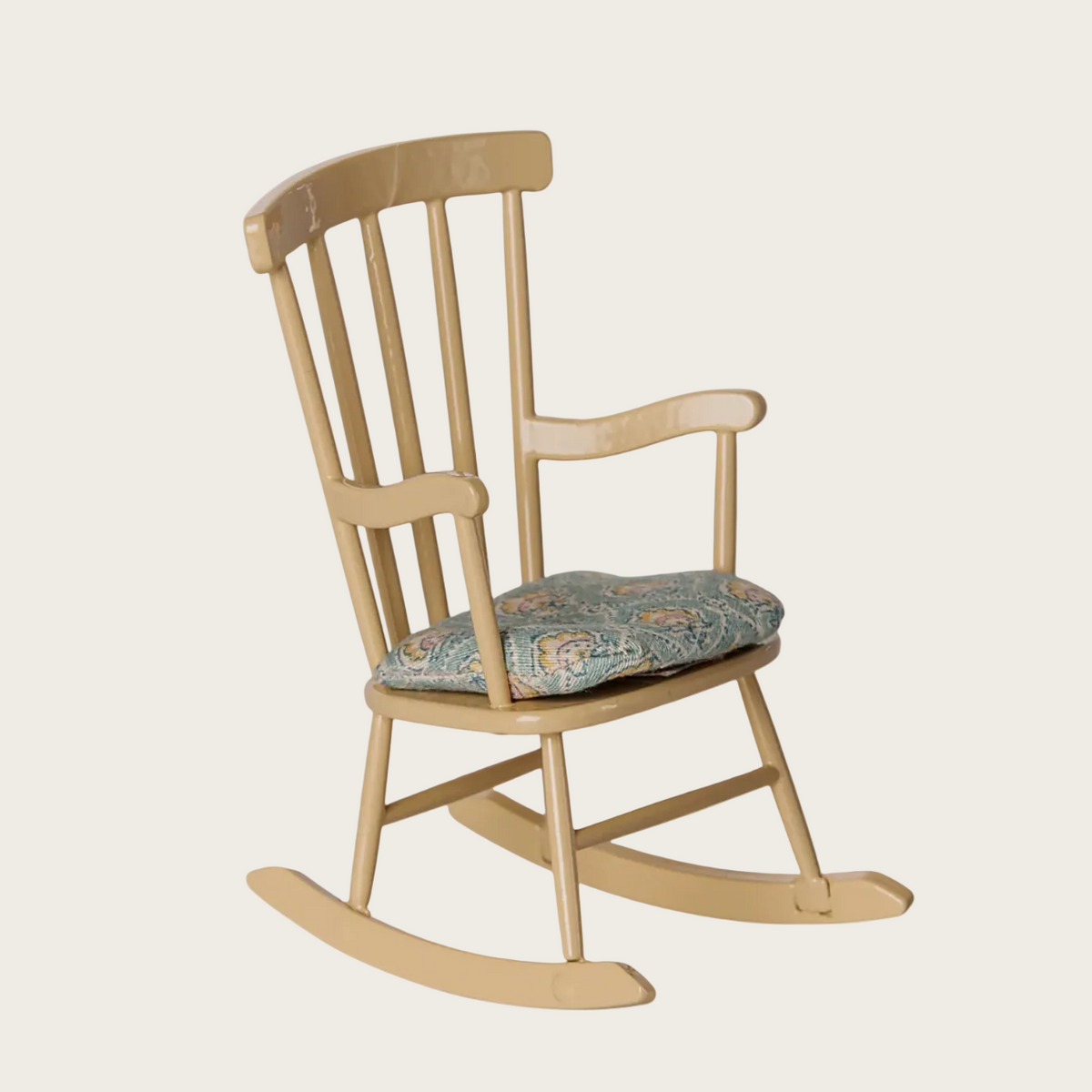 A wooden rocking chair with a floral-patterned cushion. The chair has a light natural wood finish with a blue, green, and beige patterned cushion.