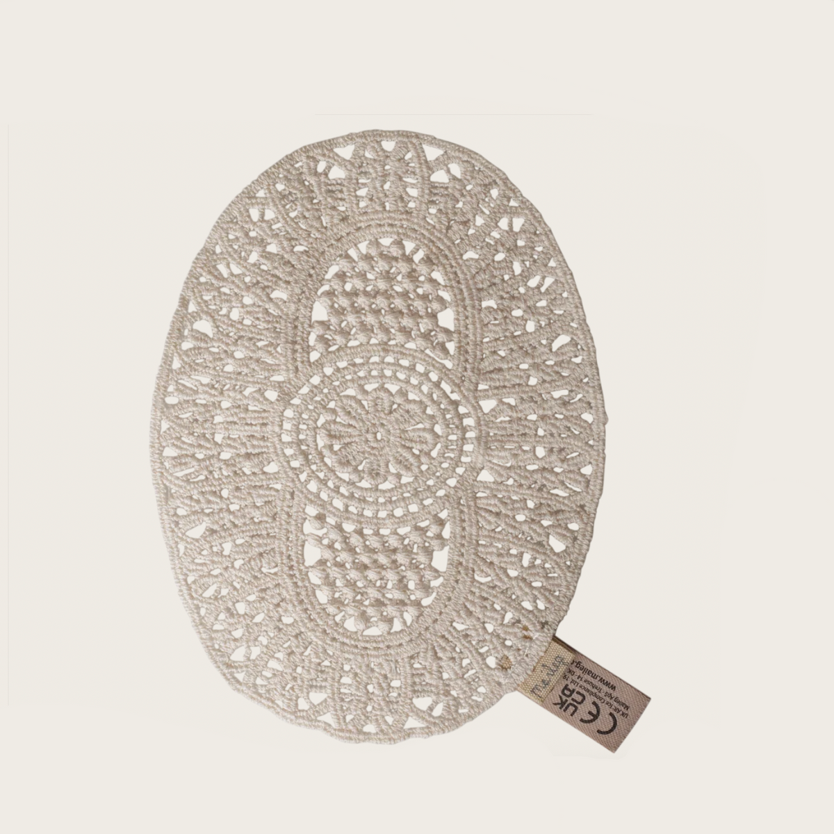 An off-white crocheted oval rug with intricate openwork patterns.