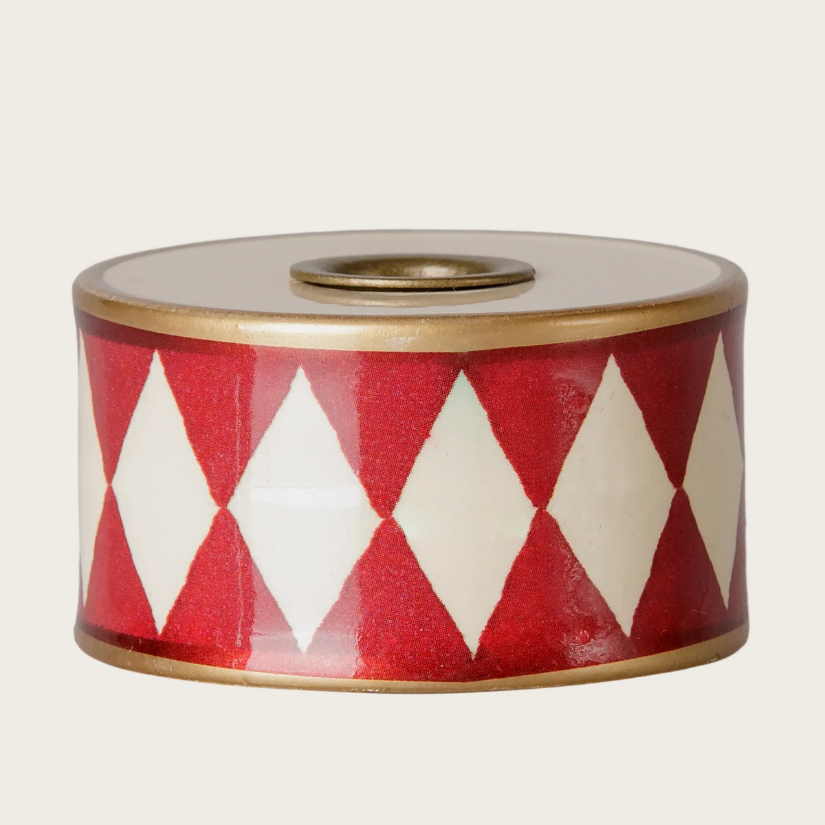 A cylindrical candle holder drum with a red and white diamond pattern and a gold-toned top.